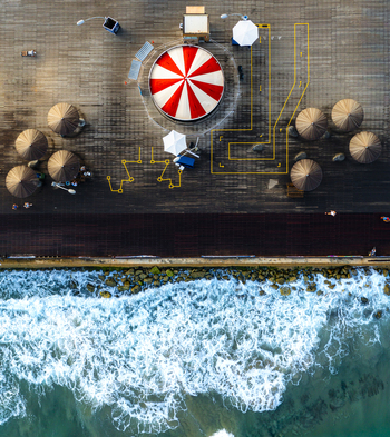 Aerial view of Tel Aviv Port featuring a red and white striped structure on a wooden deck with parasols and yellow lines near the sea in Tel Aviv Yafo Tel Aviv District Israel. Aerial view of Tel Aviv Port featuring a red and white striped structure on a wooden deck with parasols and yellow lines near the sea in Tel Aviv Yafo Tel Aviv District Israel.