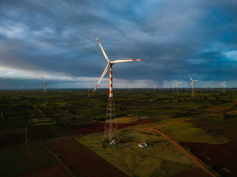 Aerial view of a wind farm with multiple wind turbines standing in a rural landscape under a dramatic cloudy sky in Hampi Karnataka India.