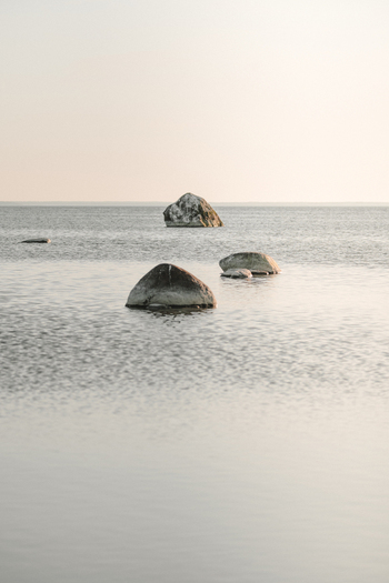 View of large glacial boulders resting in the calm shallow waters of the Baltic Sea off the coast of Vormsi Laane County Estonia.
