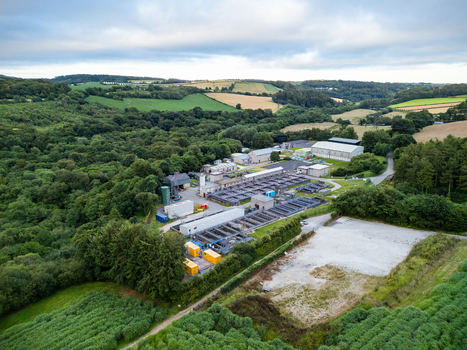 Aerial view of a water treatment facility with rectangular tanks and industrial buildings surrounded by dense woodland and green fields in Restormel England United Kingdom. Aerial view of a water treatment facility with rectangular tanks and industrial buildings surrounded by dense woodland and green fields in Restormel England United Kingdom.