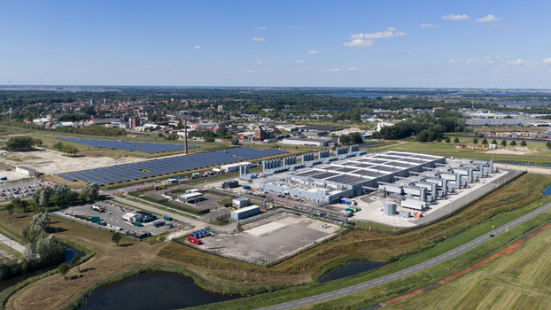 Aerial view of a large industrial facility and an adjacent solar farm with rows of photovoltaic panels Winschoten Groningen Netherlands.