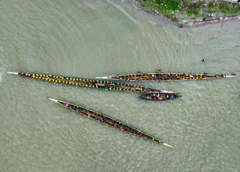 Baghabari Rajshahi Division Bangladesh 20 August 2022 Aerial view of long traditional racing boats filled with rowers in yellow shirts competing on the river.