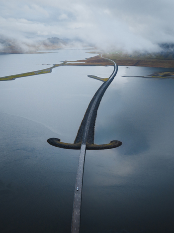 Aerial view of a captivating sword bridge stretches across the tranquil water connecting landmasses under a blanket of ethereal mist Snæfellsnes Eyja og Miklaholtshreppur Iceland. Aerial view of a captivating sword bridge stretches across the tranquil water connecting landmasses under a blanket of ethereal mist Snæfellsnes Eyja og Miklaholtshreppur Iceland.