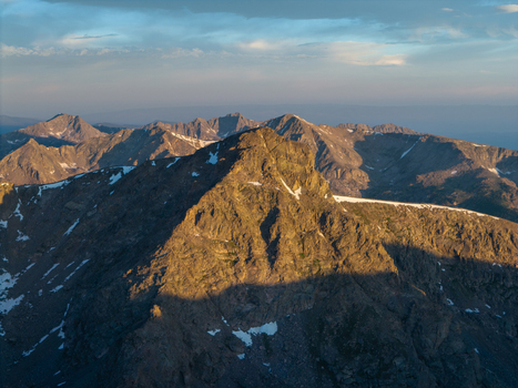Aerial view of the rugged Mount of the Holy Cross in the Sawatch Range featuring rocky peaks lingering snow patches and warm golden hour light in Vail Colorado United States. Aerial view of the rugged Mount of the Holy Cross in the Sawatch Range featuring rocky peaks lingering snow patches and warm golden hour light in Vail Colorado United States.