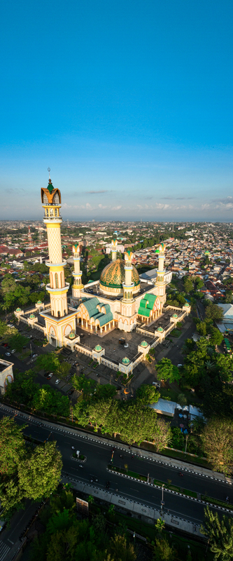 Aerial view of the Islamic Center NTB Hubbul Wathan Great Mosque with its golden dome and minaret set in the urban landscape of Kecamatan Selaparang Nusa Tenggara Barat Indonesia. Aerial view of the Islamic Center NTB Hubbul Wathan Great Mosque with its golden dome and minaret set in the urban landscape of Kecamatan Selaparang Nusa Tenggara Barat Indonesia.