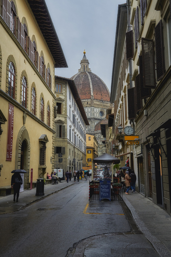 Florence Tuscany Italy 05 May 2022 View of the Florence Cathedral dome rising above a narrow historic street with pedestrians and traditional architecture in Florence Tuscany Italy.