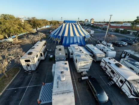 Aerial view of a vibrant blue and white circus tent rising amidst a sea of RVs in a parking lot casting long shadows under a clear sky St. Augustine Florida United States. Aerial view of a vibrant blue and white circus tent rising amidst a sea of RVs in a parking lot casting long shadows under a clear sky St. Augustine Florida United States.