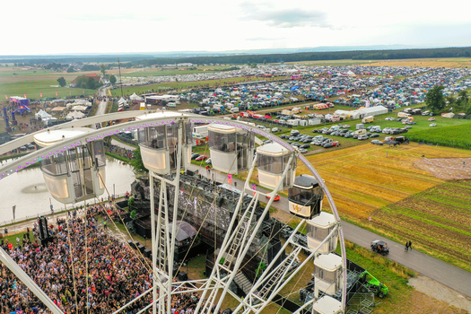 Herzogenaurach Germany 24 July 2025 Aerial view of the Open Beatz Festival featuring a large Ferris wheel a massive crowd and expansive festival grounds under a cloudy sky.