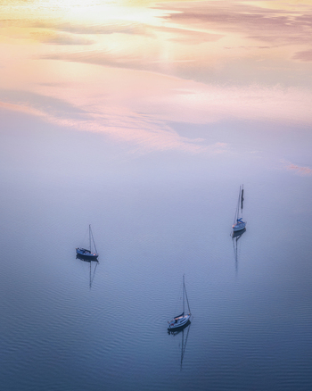 Aerial view of three sailboats floating on the calm waters of Dublin Port at sunset in Dublin County Dublin Ireland. Aerial view of three sailboats floating on the calm waters of Dublin Port at sunset in Dublin County Dublin Ireland.