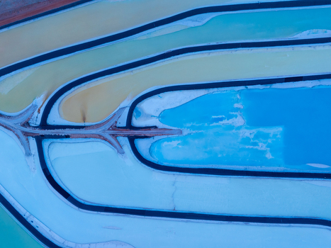 Aerial view of the vibrant blue and yellow Potash Ponds showing the geometric patterns of the evaporation pools in the desert landscape Moab Utah United States.