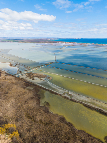 Aerial view of the colorful salt pans of Lake Atanasovsko with dikes and the Black Sea coast under a blue sky in Burgas Burgas Bulgaria. Aerial view of the colorful salt pans of Lake Atanasovsko with dikes and the Black Sea coast under a blue sky in Burgas Burgas Bulgaria.