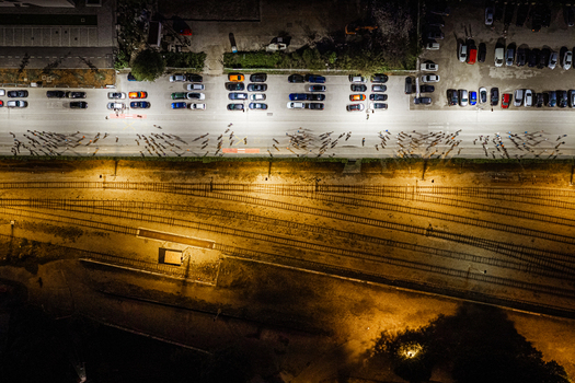Aerial view of a street with parked cars and a group of people walking along the road at night adjacent to illuminated railway tracks in Pula Istria County Croatia. Aerial view of a street with parked cars and a group of people walking along the road at night adjacent to illuminated railway tracks in Pula Istria County Croatia.