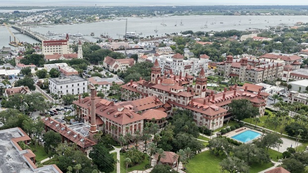 Aerial view of Flagler College featuring its historic Spanish Renaissance architecture red tiled roofs lush green courtyards and swimming pool in St. Augustine Florida United States. Aerial view of Flagler College featuring its historic Spanish Renaissance architecture red tiled roofs lush green courtyards and swimming pool in St. Augustine Florida United States.