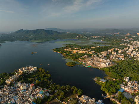 Aerial view of the historic city featuring its iconic lakes lush green hills and dense urban architecture under a clear sky Udaipur Rajasthan India.
