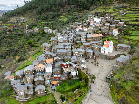 Aerial view of the quaint village nestled amidst terraced hillsides with the striking white church standing prominently in the village square Piódão Arganil Portugal. Aerial view of the quaint village nestled amidst terraced hillsides with the striking white church standing prominently in the village square Piódão Arganil Portugal.
