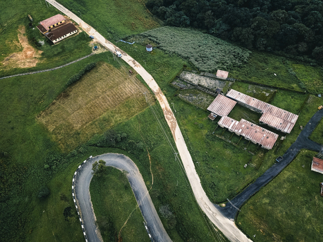 Aerial view of winding roads snaking through verdant landscapes past rustic buildings and cultivated fields under a soft light Obudu Cross River Nigeria.