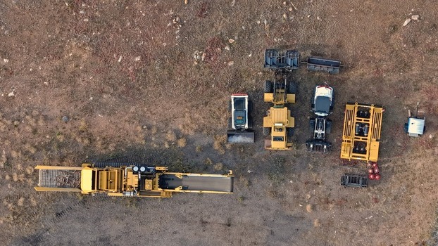 Aerial view of heavy construction machinery including a large tracked conveyor a loader and other industrial equipment parked on a dirt lot in Golden Colorado United States.