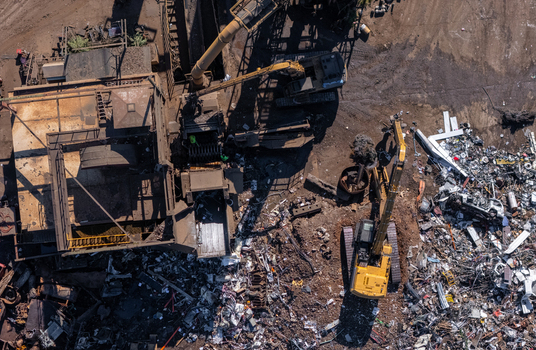 Aerial view of a scrap metal facility with large excavators sorting through piles of discarded metal and industrial debris in Kalamazoo Michigan United States. Aerial view of a scrap metal facility with large excavators sorting through piles of discarded metal and industrial debris in Kalamazoo Michigan United States.