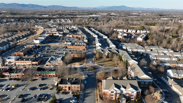 Aerial view of a residential neighborhood featuring apartment buildings a central roundabout parking lots and surrounding trees with distant mountains in Lynchburg Virginia United States.