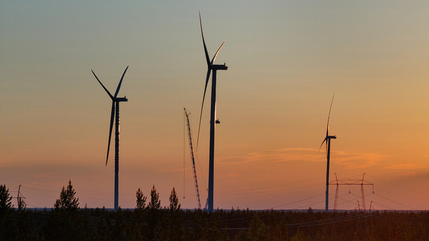 Aerial view of Metsalamminkangas Tuulipuisto wind turbines at sunset with a construction crane and power lines over a forest in Siikalatva Pohjois Pohjanmaa Finland. Aerial view of Metsalamminkangas Tuulipuisto wind turbines at sunset with a construction crane and power lines over a forest in Siikalatva Pohjois Pohjanmaa Finland.