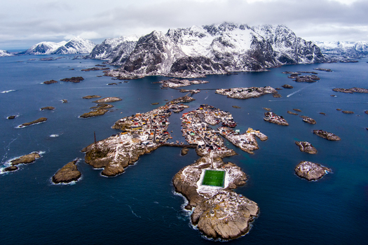 Aerial view of the iconic football pitch in the fishing village of Henningsvaer surrounded by snow capped mountains and the sea in Nordland Norway.