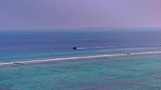 Aerial view of a speedboat cruising across turquoise ocean water.