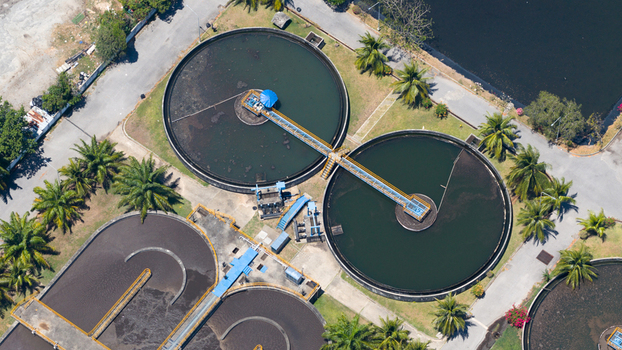 Aerial view of a wastewater treatment plant with circular sedimentation tanks surrounded by palm trees and asphalt paths in Phuket Phuket Thailand. Aerial view of a wastewater treatment plant with circular sedimentation tanks surrounded by palm trees and asphalt paths in Phuket Phuket Thailand.