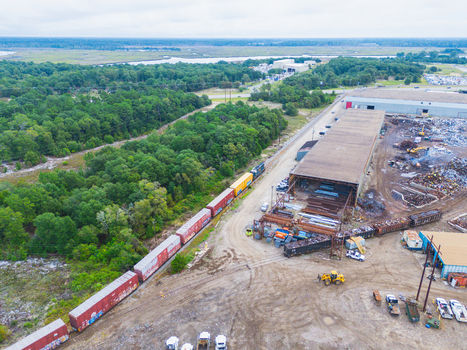 Wilmington United States 18 September 2026 Aerial view of a freight train passing through an industrial rail yard with scrap metal piles and warehouses.