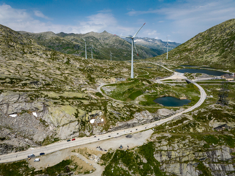 View of Sankt Gotthard Pass with wind turbines and a winding road through the rocky mountain landscape in Airolo Ticino Switzerland.