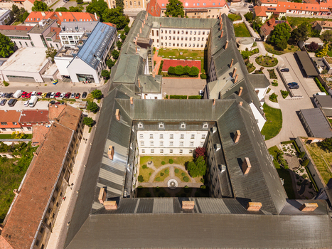Aerial view of a large historic building with inner courtyards and green rooftops surrounded by urban streets in Trnava Trnava Region Slovakia. Aerial view of a large historic building with inner courtyards and green rooftops surrounded by urban streets in Trnava Trnava Region Slovakia.