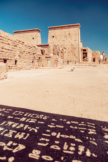 View of the ancient Philae Temple complex featuring stone pylons with detailed carvings and hieroglyphs under a clear blue sky in Aswan Aswan Governorate Egypt. View of the ancient Philae Temple complex featuring stone pylons with detailed carvings and hieroglyphs under a clear blue sky in Aswan Aswan Governorate Egypt.