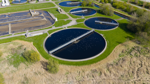 Aerial view of the circular clarifier tanks at the RWZI Geestmerambacht wastewater treatment plant with rotating bridges and seagulls on the water in Netherlands. Aerial view of the circular clarifier tanks at the RWZI Geestmerambacht wastewater treatment plant with rotating bridges and seagulls on the water in Netherlands.