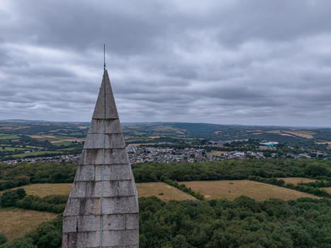 Aerial view of the stone obelisk of Bodmin Beacon rising above surrounding lush green fields dense woodland and the town of Bodmin under a cloudy sky. Bodmin Cornwall United Kingdom. Aerial view of the stone obelisk of Bodmin Beacon rising above surrounding lush green fields dense woodland and the town of Bodmin under a cloudy sky. Bodmin Cornwall United Kingdom.