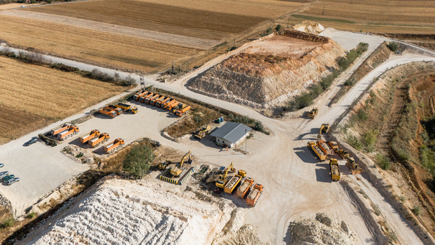Aerial view of the quarry site with excavators and dump trucks parked near piles of stone and gravel surrounded by agricultural fields in Besenovo Vojvodina Serbia. Aerial view of the quarry site with excavators and dump trucks parked near piles of stone and gravel surrounded by agricultural fields in Besenovo Vojvodina Serbia.