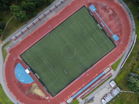 Aerial view of a sports centre with a green soccer field and a red running track wet from rain in Wieliczka Lesser Poland Voivode Poland. Aerial view of a sports centre with a green soccer field and a red running track wet from rain in Wieliczka Lesser Poland Voivode Poland.