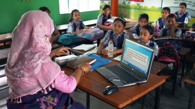 View of a teacher using a laptop in a classroom Bangladesh.