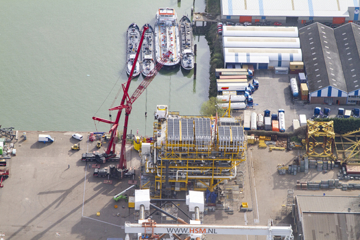 Aerial view of Rotterdam Harbour showing a large industrial platform under construction a red mobile crane and cargo ships docked at the quay in Rotterdam South Holland Netherlands. Aerial view of Rotterdam Harbour showing a large industrial platform under construction a red mobile crane and cargo ships docked at the quay in Rotterdam South Holland Netherlands.