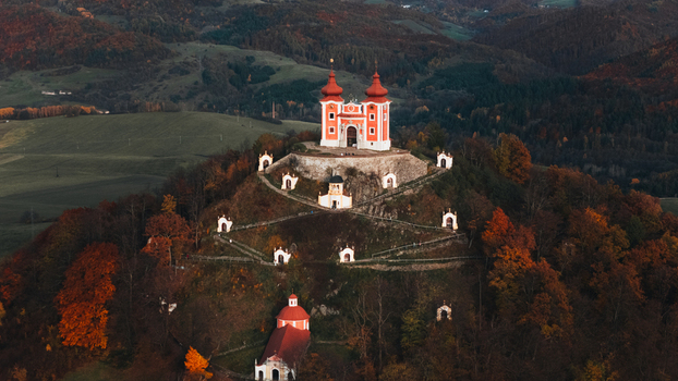 Aerial view of the Kalvaria Banska Stiavnica baroque church complex on a hill surrounded by vibrant autumn foliage and rolling hills in Banska Stiavnica Banskobystricky kraj Slovakia.