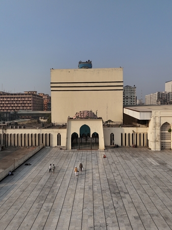 Aerial view of the Baitul Mukarram National Mosque with its cube shaped architecture expansive marble courtyard and people walking in the plaza in Dhaka Dhaka Division Bangladesh. Aerial view of the Baitul Mukarram National Mosque with its cube shaped architecture expansive marble courtyard and people walking in the plaza in Dhaka Dhaka Division Bangladesh.