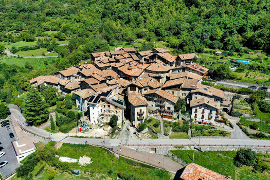 Aerial view of the medieval stone village of Canale di Tenno with traditional terracotta rooftops nestled among lush green hills in Ville del Monte Trentino Alto Adige Italy. Aerial view of the medieval stone village of Canale di Tenno with traditional terracotta rooftops nestled among lush green hills in Ville del Monte Trentino Alto Adige Italy.