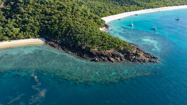 Aerial view of Whitehaven Beach featuring pristine white sand turquoise waters coral reefs and lush tropical forest with boats anchored in the Whitsundays Queensland Australia.