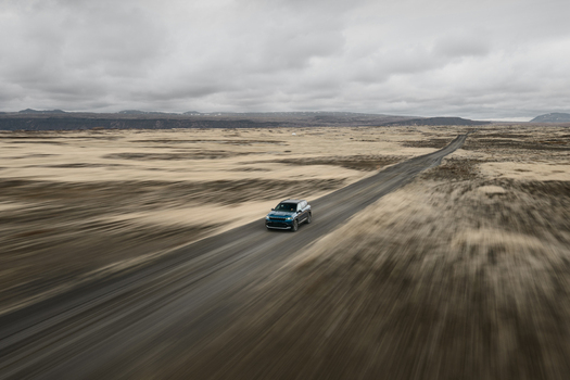 Aerial view of a car driving on a long straight road through the vast volcanic landscape near Hlidarvatn in Sveitarfelagid Olfus Iceland. Aerial view of a car driving on a long straight road through the vast volcanic landscape near Hlidarvatn in Sveitarfelagid Olfus Iceland.