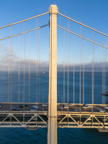 Aerial view of the San Francisco Oakland Bay Bridge with traffic on the suspension structure above the bay under a clear sky San Francisco California United States. Aerial view of the San Francisco Oakland Bay Bridge with traffic on the suspension structure above the bay under a clear sky San Francisco California United States.