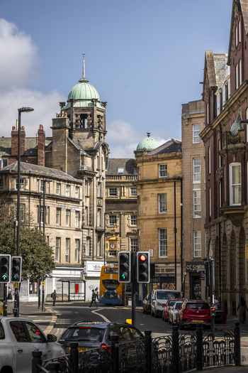 Newcastle upon Tyne United Kingdom 13 July 2026 View of historic sandstone buildings with green domes a yellow double decker bus traffic lights and cars on a city street. Newcastle upon Tyne United Kingdom 13 July 2026 View of historic sandstone buildings with green domes a yellow double decker bus traffic lights and cars on a city street.