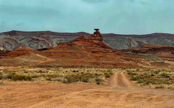 View of the iconic Mexican Hat rock formation in the desert landscape of Monument Valley with red sandstone cliffs and a dirt road in Oljato Monument Valley Utah United States.