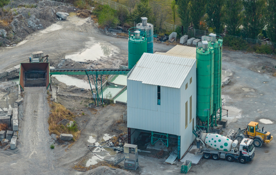 Loriol sur Drome France 26 July 2026 Aerial view of a concrete batching plant with aggregate conveyor storage silos and a mixer truck in an industrial facility.