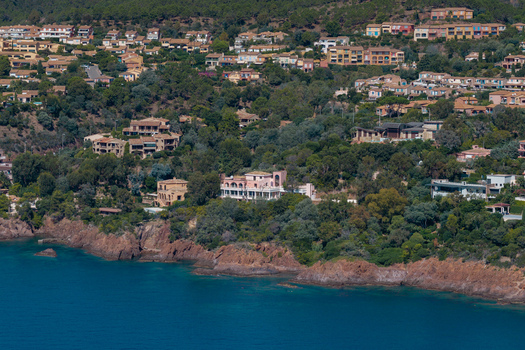 Aerial view of Le Trayas featuring Mediterranean villas nestled among lush green trees and rocky cliffs overlooking the blue sea in Saint Raphael Provence Alpes Cote d Azur France. Aerial view of Le Trayas featuring Mediterranean villas nestled among lush green trees and rocky cliffs overlooking the blue sea in Saint Raphael Provence Alpes Cote d Azur France.