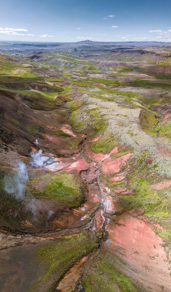 Aerial view of Grensdalur geothermal valley featuring colorful volcanic soil steaming vents and a winding stream cutting through the rugged landscape of Sveitarfelagid Olfus Iceland. Aerial view of Grensdalur geothermal valley featuring colorful volcanic soil steaming vents and a winding stream cutting through the rugged landscape of Sveitarfelagid Olfus Iceland.
