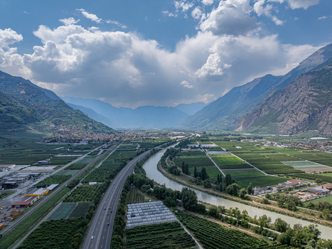 Aerial view of the Rhone River flowing through the valley with agricultural fields a highway and mountains in the background in Riddes Valais Switzerland. Aerial view of the Rhone River flowing through the valley with agricultural fields a highway and mountains in the background in Riddes Valais Switzerland.