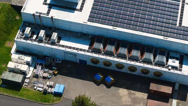 Aerial view of the Data Centre facility featuring solar panels on the roof and large industrial cooling fans along the white facade in Wellingborough England United Kingdom. Aerial view of the Data Centre facility featuring solar panels on the roof and large industrial cooling fans along the white facade in Wellingborough England United Kingdom.